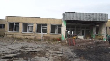 Ukrayna 'da savaş. 2022 Rus istilası Ukrayna. Altyapı tahribatı. Sivil halkın terörü. Savaş suçları. Okula giriş bombardımanla yok edildi. Kamera soldan hareket ediyor.