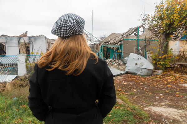 War in Ukraine. 2022 Russian invasion of Ukraine. Countryside. The girl looks at the house destroyed by shelling. Terror of the civilian population. War crimes