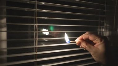Kesinti. Enerji krizi. Altyapı tahribatı. Elektrik kesintisi konsepti. Panjurlu (yakın çekim) bir pencerede yanan bir kibrit. Sabit Kamera