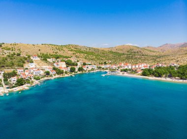 Hırvatistan. Yaz. Güneşli bir gün. Adriyatik Denizi kıyısında. Deniz kenarında küçük bir kasaba. Tatil sezonu. Popüler turist mekanı. Drone. Hava görünümü