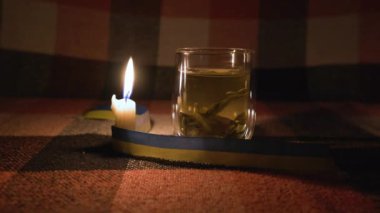 Kesinti. Elektrik kesintisi konsepti. Ukrayna 'nın ulusal sembolü olan sarı-mavi kurdeleli yanan bir mum ışığında şeffaf bir fincan bitki çayı. Sabit Kamera