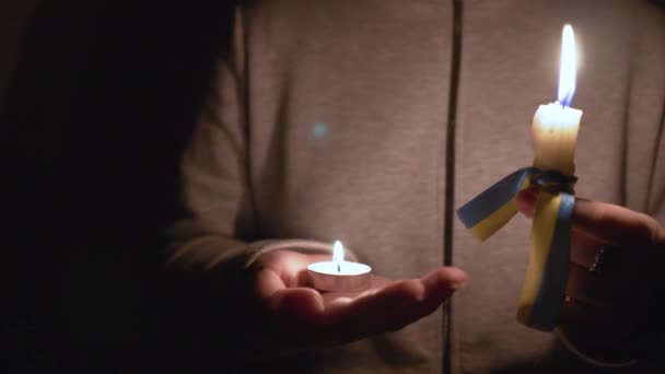 停电了能源危机 停电的概念 女孩手里拿着两支燃烧的蜡烛 一支黄色 蓝色缎带 乌克兰的国家象征 摄像机从左移到右移 — 图库视频影像