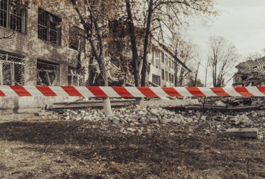 Okul bombardımandan zarar gördü. Ön planda bir uyarı kaseti var. Ukrayna 'da savaş. Rus işgali Ukrayna 'da. Altyapı tahribatı. Sivil halkın terörü