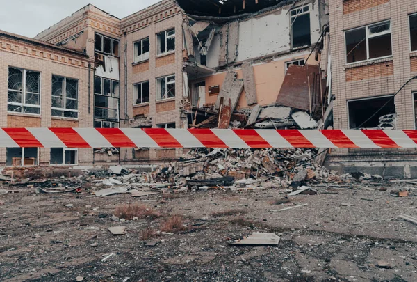 Stock image School damaged by shelling. There is a warning tape in the foreground. War in Ukraine. Russian invasion of Ukraine. Destruction of infrastructure. Terror of the civilian population