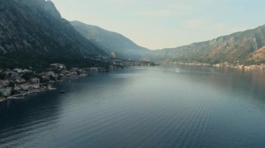 Karadağ. Adriyatik Denizi. Kotor Körfezi. Popüler turist mekanı. Sahildeki köy. Turuncu kiremit çatılı evler. Yaz. Turizm sezonu. Drone. Uç! Hava görüntüsü. Kamera soldan sağa hareket ediyor.