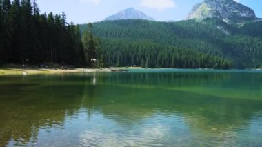 Karadağ. Zabljak. Durmitor Ulusal Parkı. Popüler turist mekanı. Yeşil kozalaklı ormanlarla çevrili kara göl. Panorama. Kamera soldan sağa hareket ediyor.