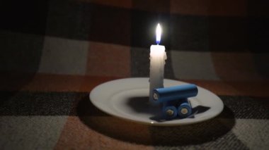 Yanan bir mumun yanında üç adet boş silindirik pil bulunur (yakın plan, kamera soldan sağa hareket eder). Elektrik kesintisi konsepti. Kesinti. Enerji krizi
