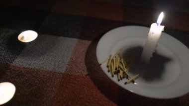 Bir avuç kibrit yanan bir mumun yanında yatar (yakından, kamera soldan sağa hareket eder). Elektrik kesintisi konsepti. Kesinti. Enerji krizi