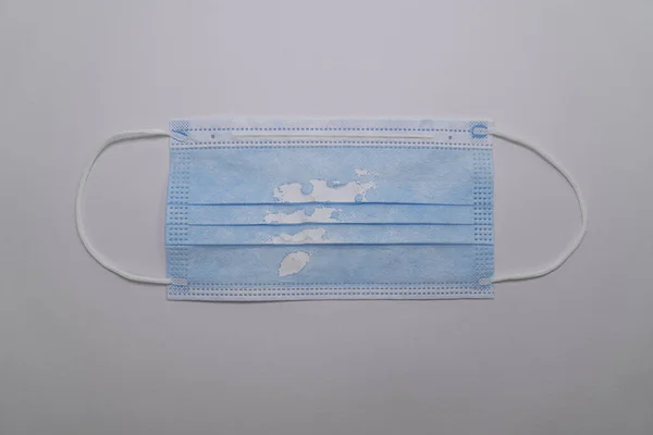 Used (damaged) blue medical mask isolated on gray background. The concept of the end of the pandemic. Cancel mask mode. No covid