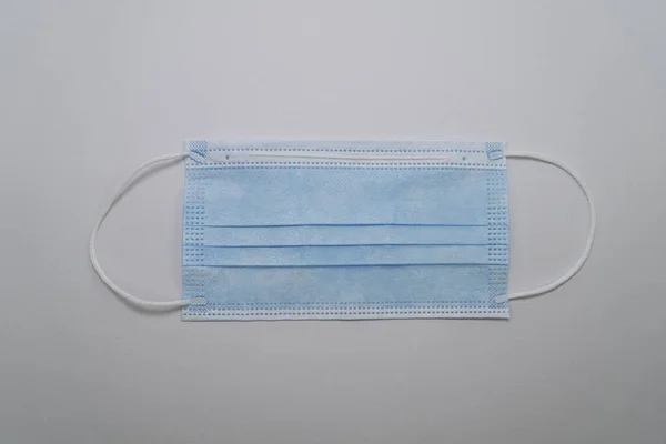 Blue medical mask isolated on a gray background (close-up). Disposable surgical face mask. Protection against coronovirus Covid-19, pollution and infections