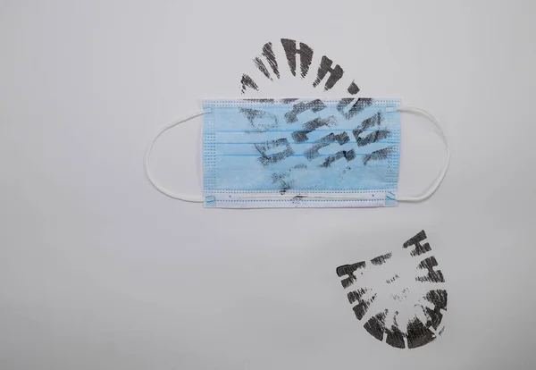 Footprint of a boot on a blue medical mask isolated on a gray background. The concept of the end of the pandemic. Zero covid