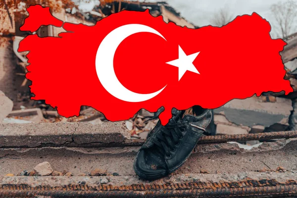 The national flag of Turkey in the form of a map of Turkey against the background of the ruins of a destroyed house. Earthquake in Turkey