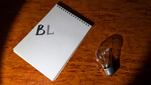 Notepad Electric Light Bulb Wooden Table Lit Spotlight Inscription Blackout — Stockvideo