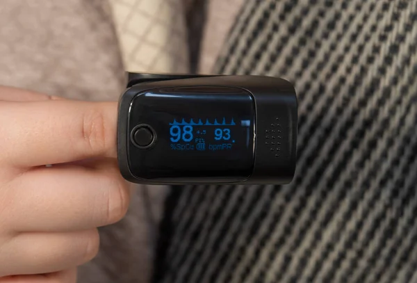 stock image An oximeter is put on a finger (close-up). Measurement of the level of oxygen in the blood. Concept of medicine, healthcare, pharmacy and home treatment