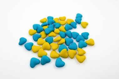 Beyaz arka planda izole edilmiş bir grup sarı ve mavi kalp şeklinde şeker. Ukrayna 'nın devlet sembolleri. Yukarıdan görüntüle
