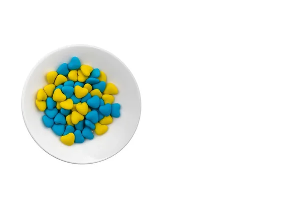 Λευκό Πιάτο Μπλε Και Κίτρινες Καραμέλες Σχήμα Καρδιάς Close Που — Φωτογραφία Αρχείου
