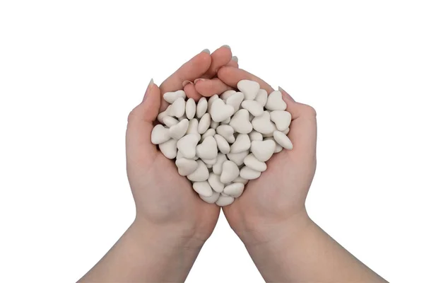 Stock image A handful of white candies in the shape of a heart in the hands, isolated on a white background. Close-up, top view