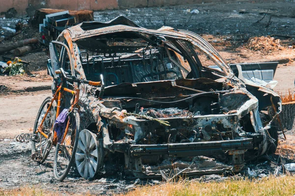 stock image A burned-out car next to a residential building destroyed by rocket fire. War in Ukraine. Terror of the civilian population