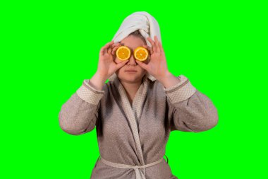 Bornozlu bir kız yeşil arka planda limonlarla gözlerini kapatır (kroma anahtarı). Sağlıklı bir yaşam tarzı. Soğuk sezon konsepti