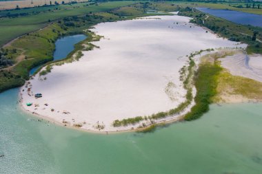 Su basmış bir taş ocağının beyaz kuvars kumu manzarası. Yapay göl kıyısında bir sahil. Kırsal kesimde. Drone. Hava görünümü