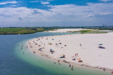Su basmış bir taş ocağının beyaz kuvars kumu manzarası. Yapay göl kıyısında bir sahil. Kırsal kesimde. Drone. Hava görünümü