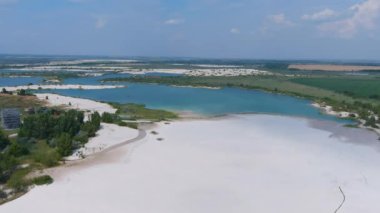 Su basmış beyaz kuvars kum ocaklarının üst görüntüsü (kamera ileri gidiyor). Mavi suyu olan güzel yapay göller. Kırsal kesimde. Drone. Hava görünümü