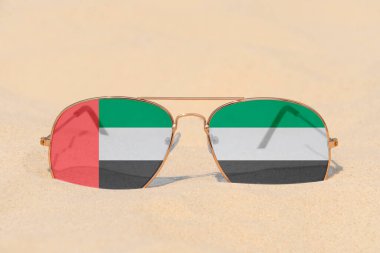 Birleşik Arap Emirlikleri bayrağı şeklinde gözlüklü güneş gözlükleri kumun üzerinde yatmaktadır. Birleşik Arap Emirlikleri 'nde yaz tatili, seyahat ve turizm kavramı. Yaz tatili. Tatil sezonu