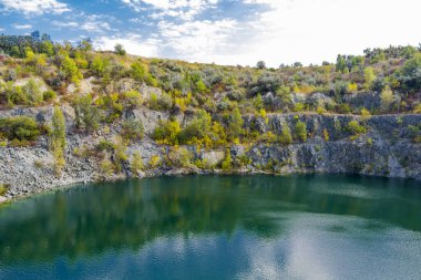 Su basmış ve terk edilmiş granit ocağını turkuaz suyla doldurmuş. Güneşli bir sonbahar günü. Drone. Hava görünümü