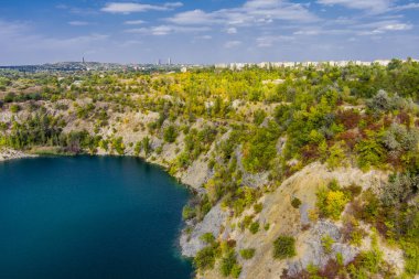 Su basmış ve terk edilmiş granit ocağını turkuaz suyla doldurmuş. Güneşli bir sonbahar günü. Drone. Hava görünümü