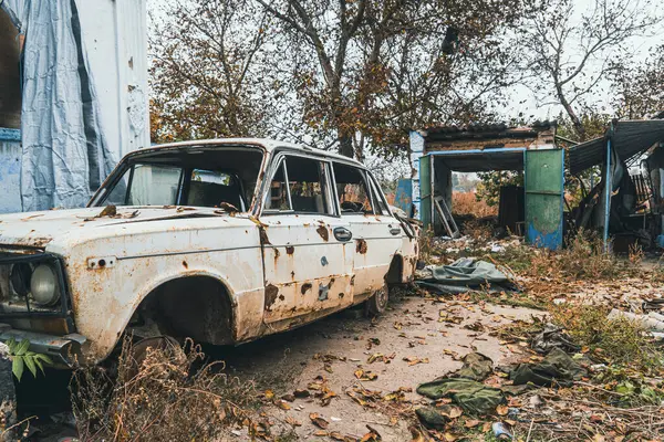 Countryside. A car in the courtyard of a house, damaged by artillery shelling. War in Ukraine. Russian invasion of Ukraine. Terror of civilians. War crimes