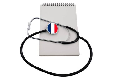 Kafası Fransa bayrağı şeklinde bir steteskop ve beyaz arka planda izole edilmiş boş bir not defteri. Fransız sağlık sistemi kavramı