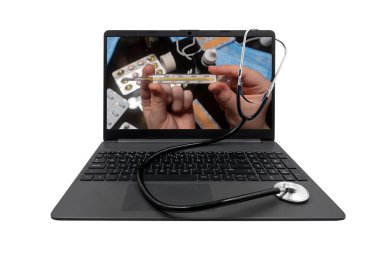 Laptop ve tıbbi steteskop beyaz arka planda izole edildi. Laptop ekranında, elinde ilaçlı bir masanın arka planına karşı bir cıva termometresi var.
