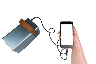Beyaz arka planda izole edilmiş bir USB kablosu ile büyük bir güç kaynağı (şarj istasyonu) ile şarj olan, elinde boş bir beyaz ekran ile akıllı telefon. Mobil güç kaynağı