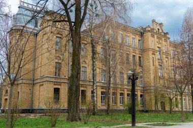Kyiv, Ukrayna - 04.05.2025: Ukrayna 'nın Kyiv kentinde önemli bir kent simgesi olan Igor Sikorsky Kyiv Politeknik Enstitüsü' nün tarihi tuğla binasının dış görünüşü. Etrafı ağaçlarla çevrili bulutlu bir gökyüzü altında kurumsal mimari