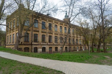 Etrafı çıplak ağaçlarla ve dolambaçlı yollarla çevrili, tarihi mimari ve doğal güzelliklerle dolu eski bir tuğla bina.