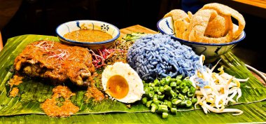 Malezya Geleneksel Tabağı: Tuzlu yumurta, sebze, keropok ve satay soslu ızgara tavukla servis edilen Nasi Kerabu