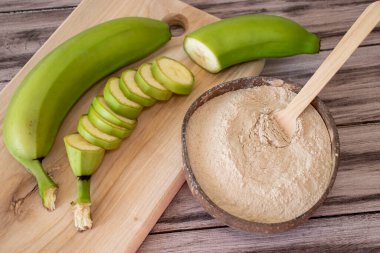 Masadaki yeşil muz unu kesme tahtasının yanında, kesilmiş muzla yüzük şeklinde..