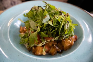 Arugula salatası ve mavi tabakta karamelize patlıcan..