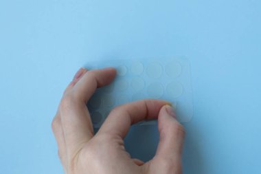 Kız çıkartmayı yırttı. Yuvarlak sivilce bantları. Evde cilt bakımı