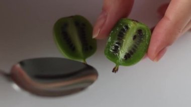 Kadın küçük bir kaşıkla aktinidia mini kivi alır.