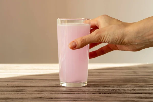 Różowa Tabletka Elektrolitu Rozpuszcza Się Wodzie Ręka Kobiety Trzyma Szklankę — Zdjęcie stockowe