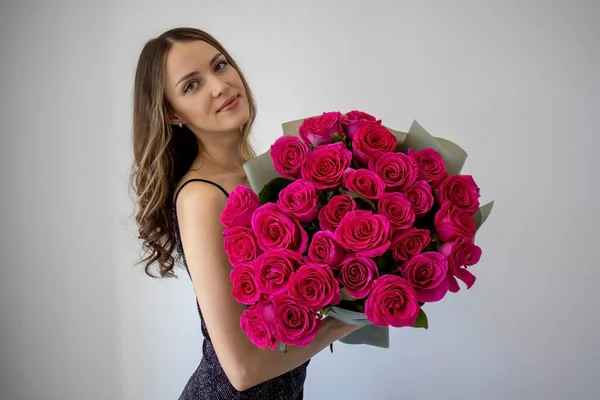 花の大きな花束を受け入れるドレスでカールを持つ美しい若い女性 ピンクのバラの女の子 — ストック写真