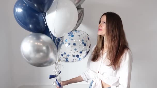 白と青の風船で美しい若い幸せな笑顔の女性 誕生日パーティーでファッショナブルなモデルの女の子 — ストック動画