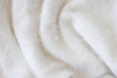 Arka plan olarak yumuşak bej örülmüş kumaş, yakın plan. Dalgalar halinde kabarık hafif süveter ya da eşarp. Uzayı metin için kopyala. Düz yerde, üst tarafta. Metin için tasarım