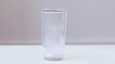 El, köpüklü hapı bir bardak suya atar. Pembe elektrolitlerin olduğu cam, spor yaparken suda çözünür..