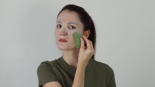 Kobieta Masująca Zieloną Kamienną Masażystką Guaszy Wierzchu Nawilżającej Białej Maski — Wideo stockowe