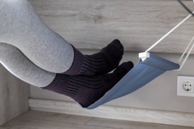 Kadınların bacakları masanın altındaki bir hamakta yatıyor. Varisli damarlar için damar sağlığı
