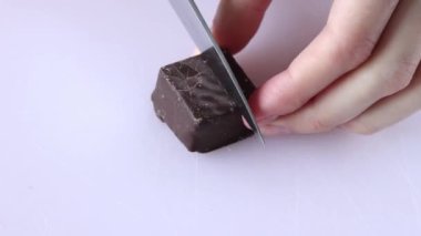 Geleneksel Türk tatlısı Pamuk Şeker. Türkçe adı Pismaniye. Nar ışığı halkası ve koyu çikolata. Bir kadın kare bir şekeri ikiye böler..