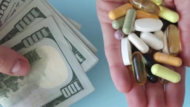 一个女人一只手拿着美元 另一只手拿着一堆药丸 昂贵药物和滥用药物的概念 — 图库视频影像