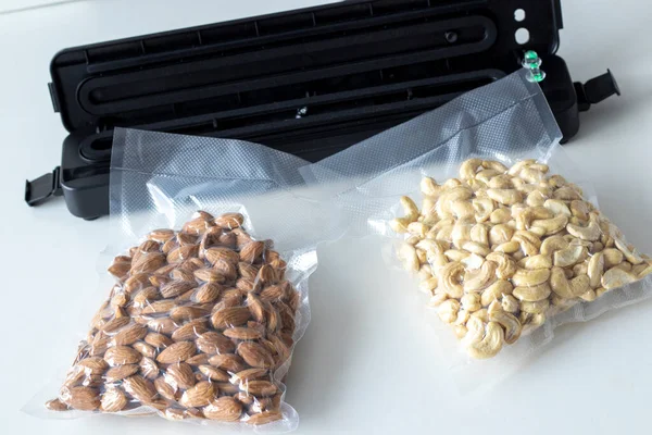 Vacuum packaging of almonds and cashew nuts for long term storage. Use vacuum packer for long term storage of products. Vacuum packaging machine in the home kitchen